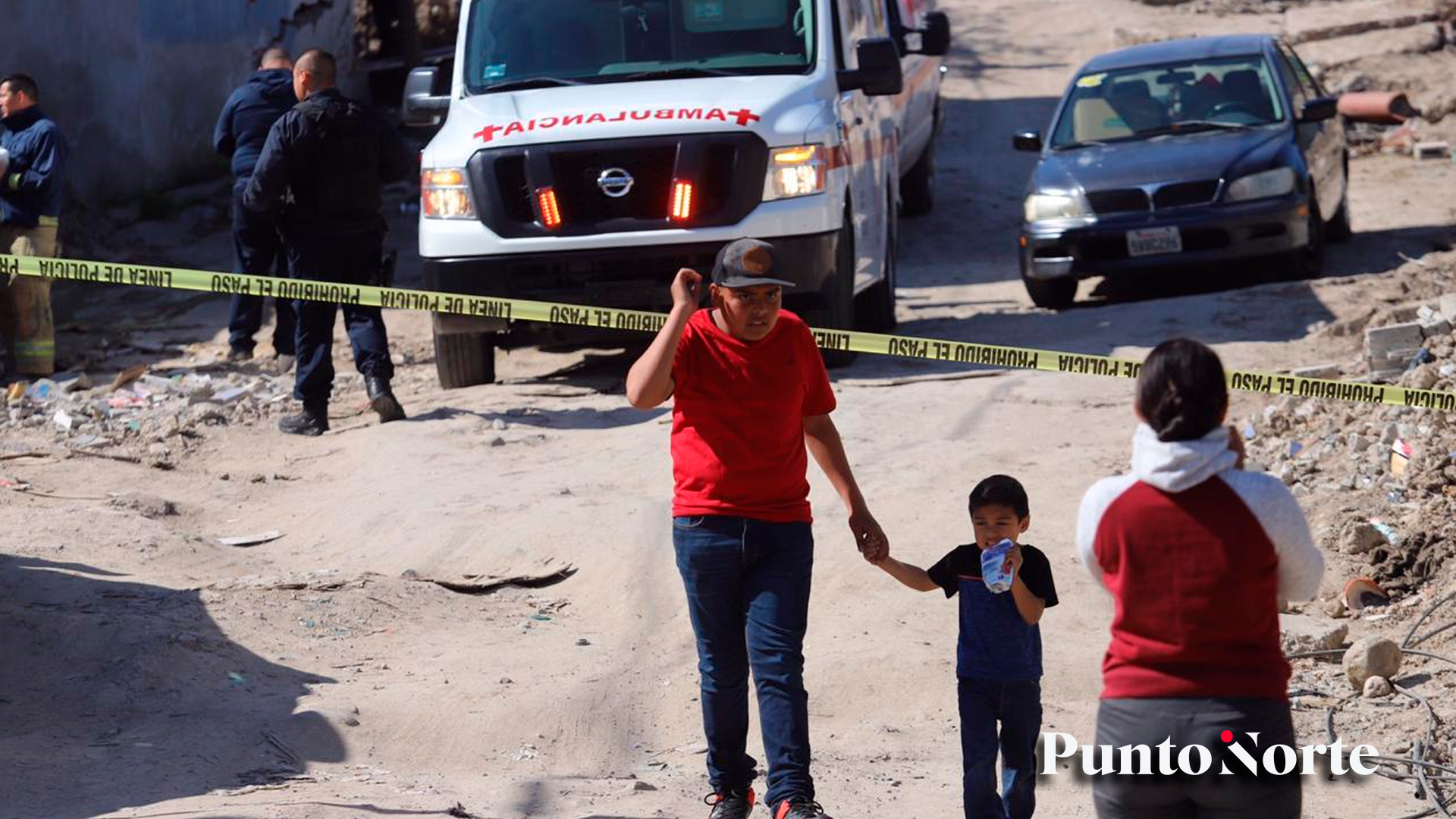 Dos niños pasan entre patrullas y ambulancias